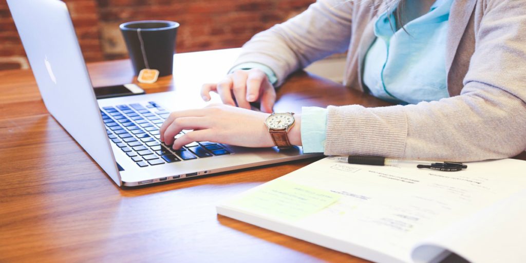 A woman's hands working on a laptop.